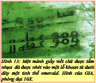 Text Box: Hình 13: Một mảnh giấy viết chữ được tẩm nhựa đã được nhét vào một lỗ khoan từ dưới đáy một tinh thể emerald. Hình của GIA, phóng đại 10X. 